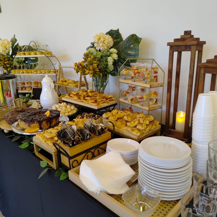 Mesa de coffee break com decoração floral para evento na Zona Sul