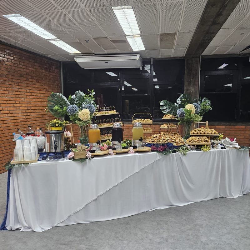 Mesa de coffee break com salgados e sucos naturais